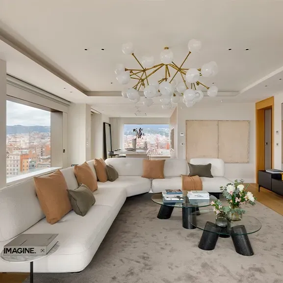 Spacious living room with curved white sofa and city skyline backdrop at Mandarin Oriental Residences.