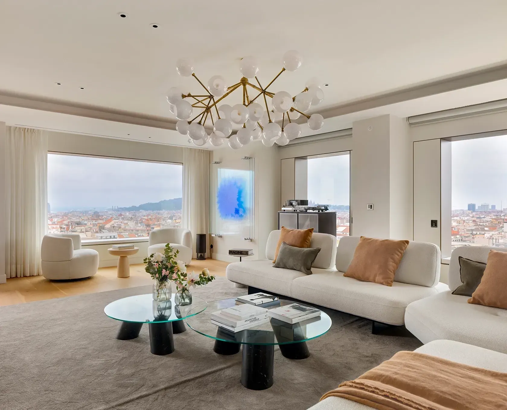 Elegant living room with panoramic city views, designer furniture, and contemporary chandelier, styled by LUV Studio for a luxury residence.