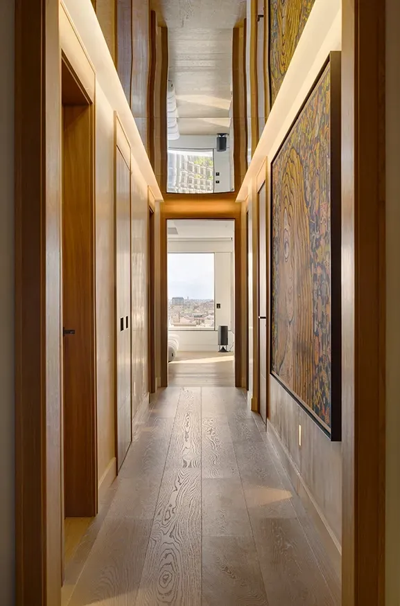 Art-filled hallway with wooden finishes and mirrored ceiling, leading to bright bedroom at Mandarin Oriental Residences.