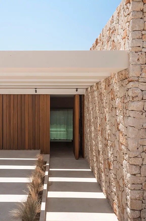 A welcoming entrance framed by stone, wood, and a light pergola.
