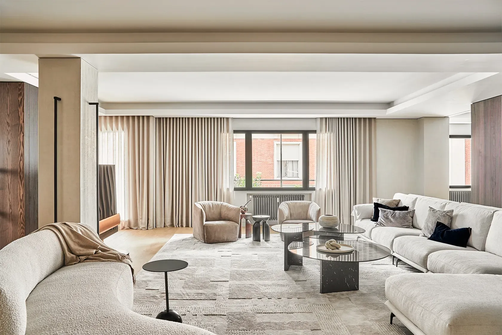 Spacious living room with neutral palette, soft sofas, designer armchairs, and large windows, showcasing elegant interior design by LUV Studio.