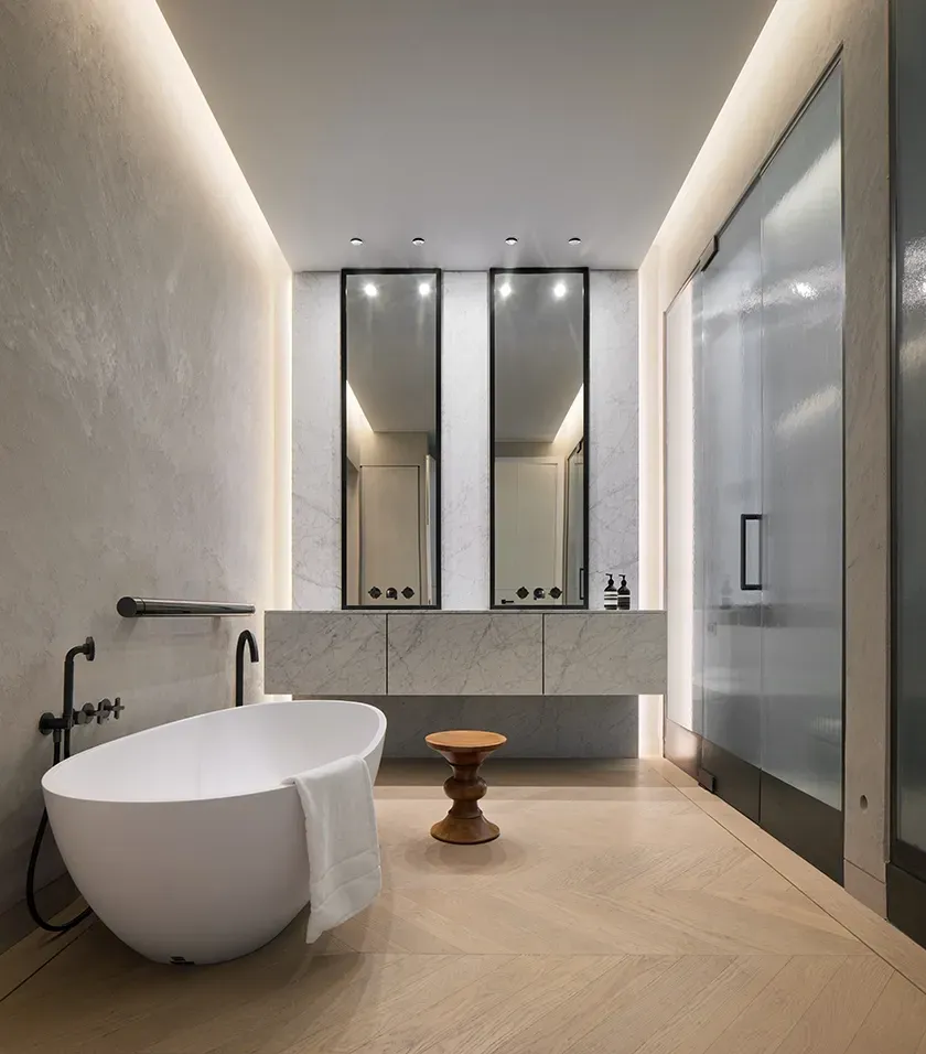 Luxury bathroom with freestanding tub, marble walls, and modern minimalist architecture.