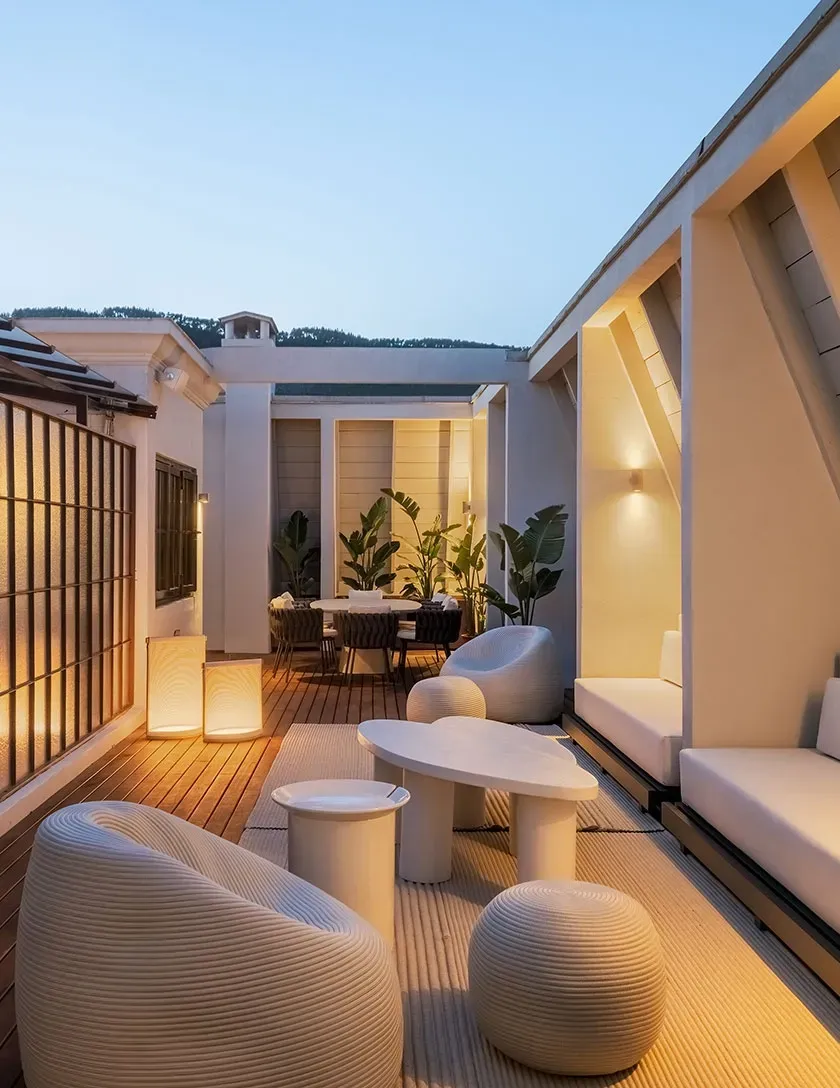 Elegant rooftop lounge with ambient lighting, modern furniture and wooden flooring in a luxury terrace.