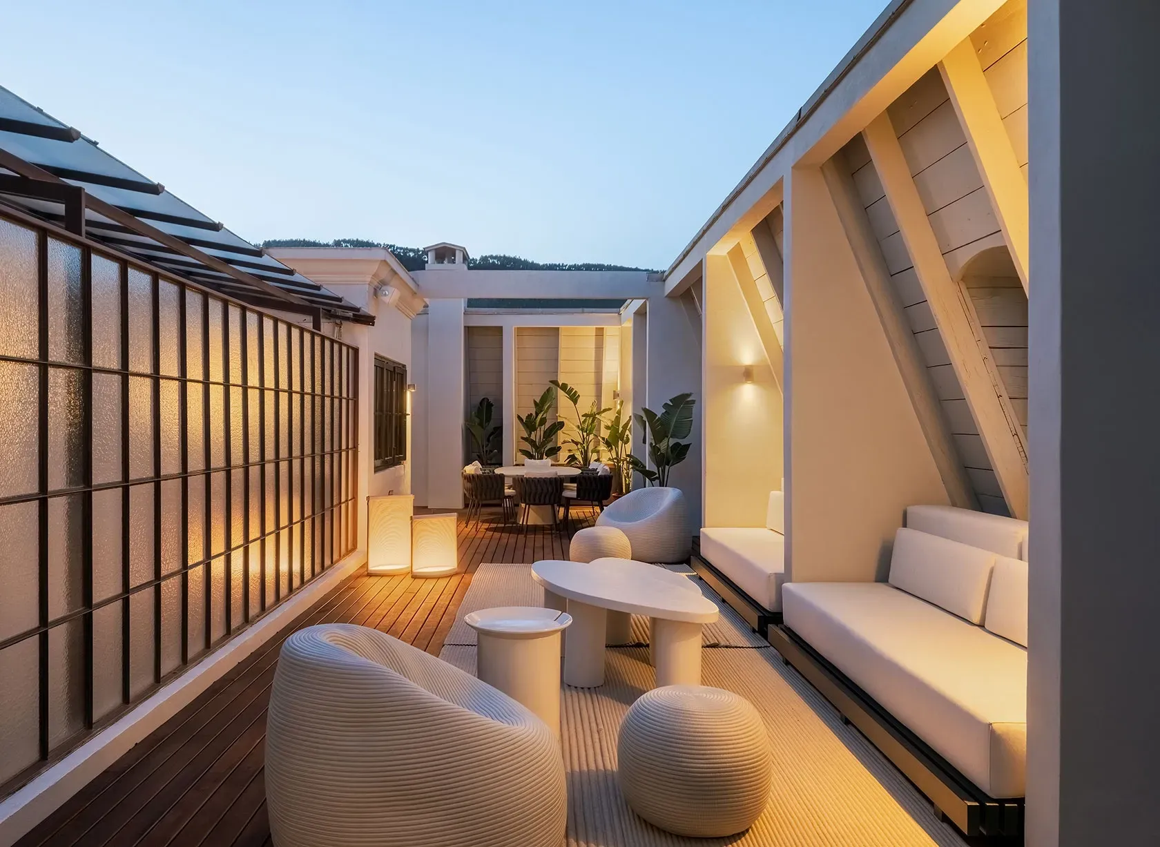 Elegant rooftop lounge with ambient lighting, modern furniture and wooden flooring in a luxury terrace.
