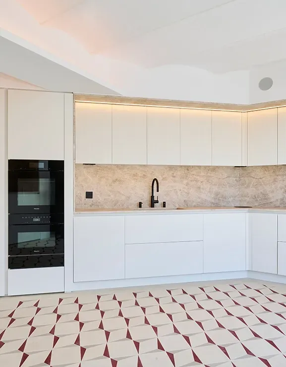 Minimalist kitchen with white cabinetry, marble backsplash, and patterned tile floor, featuring integrated appliances and warm ambient lighting.