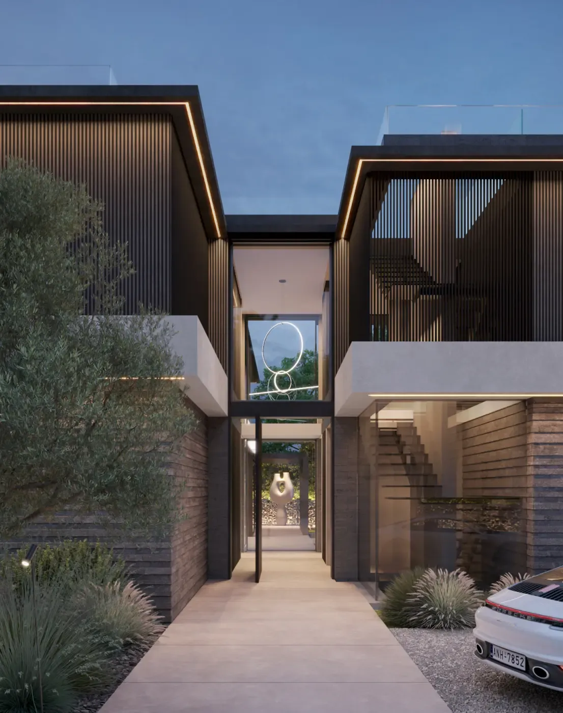 Modern luxury villa with stone façade and lush Mediterranean landscaping at the main entrance.