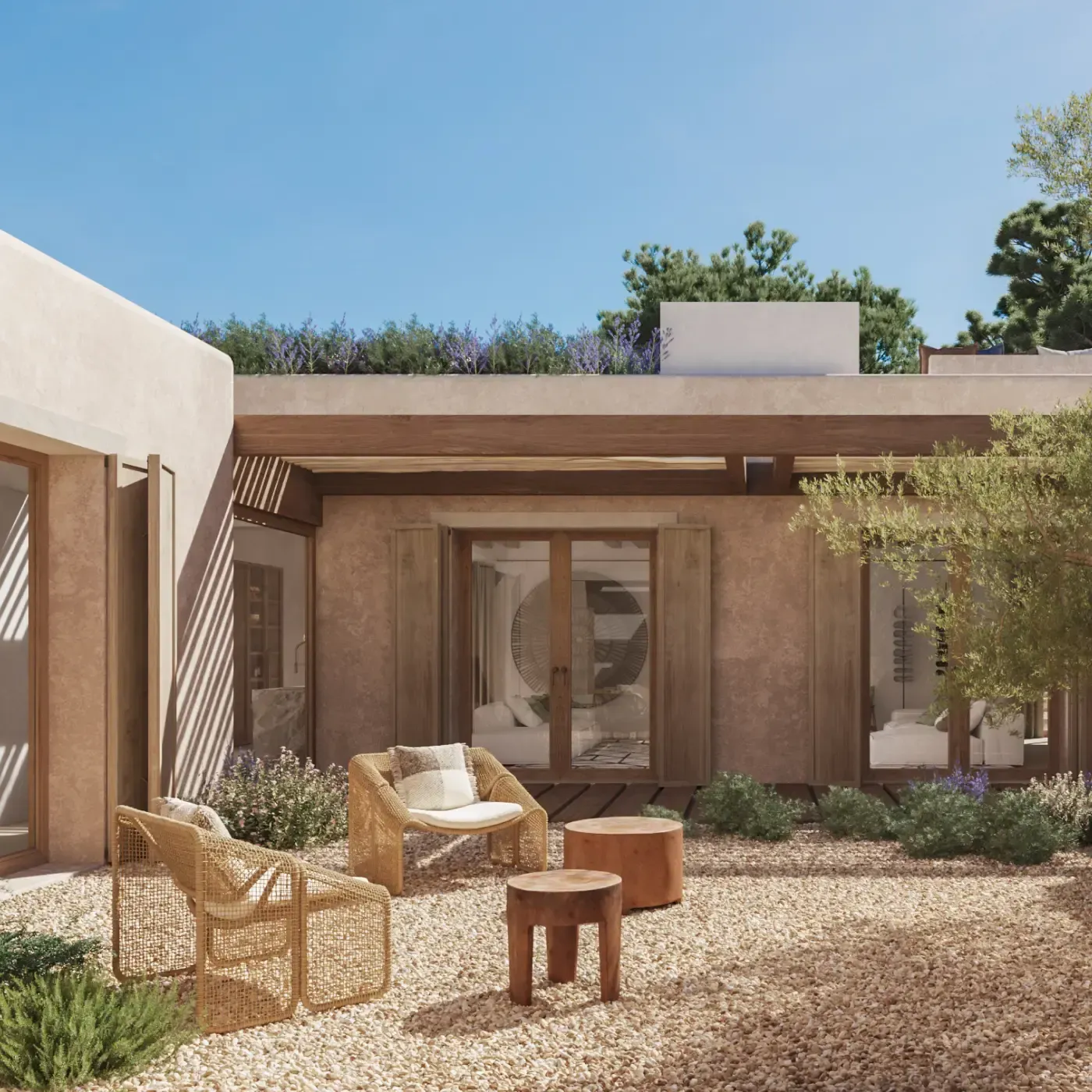 Peaceful central patio with wicker chairs, gravel flooring, lush landscaping, and an olive tree.