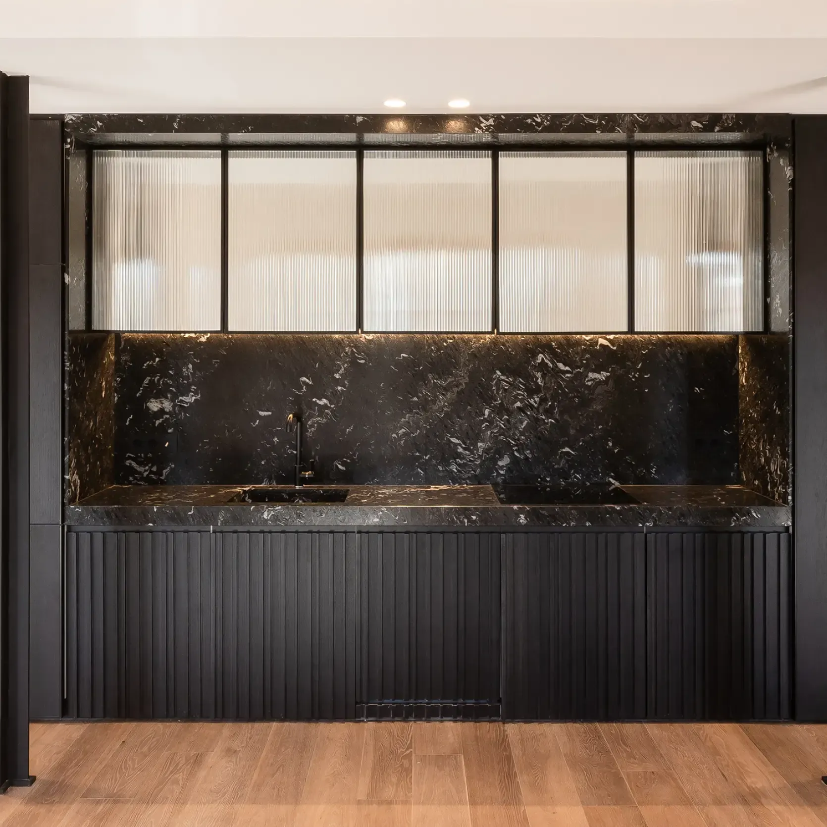 Contemporary black marble kitchen with integrated appliances by Luv Studio, blending luxury and functionality.