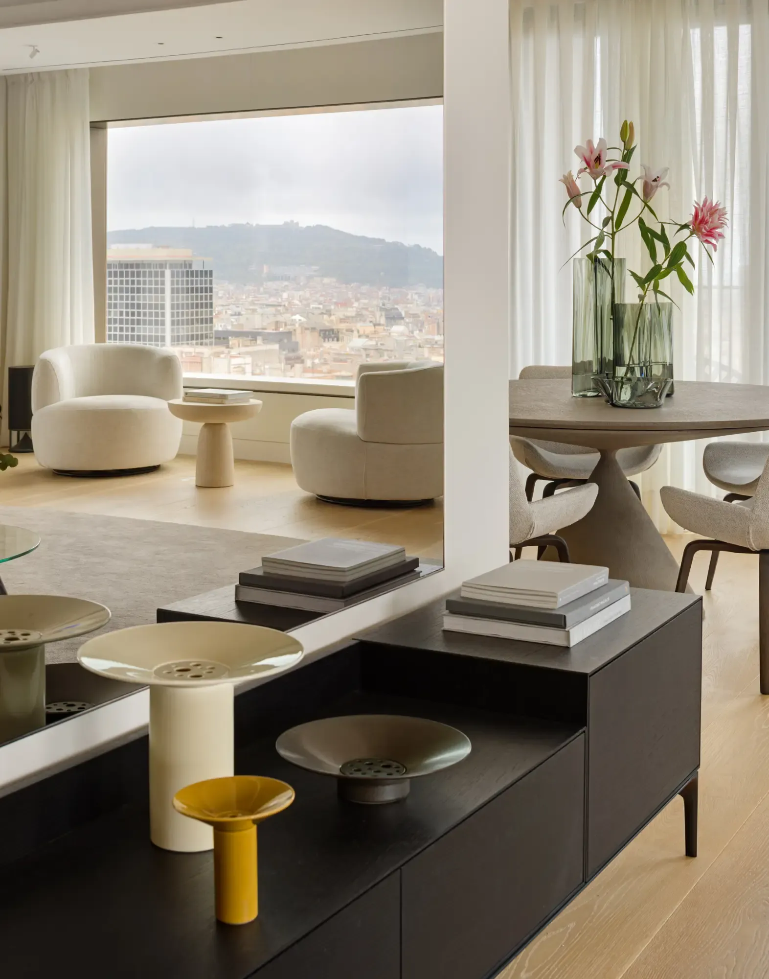 Bright living room with panoramic views, contemporary armchairs and floral arrangement