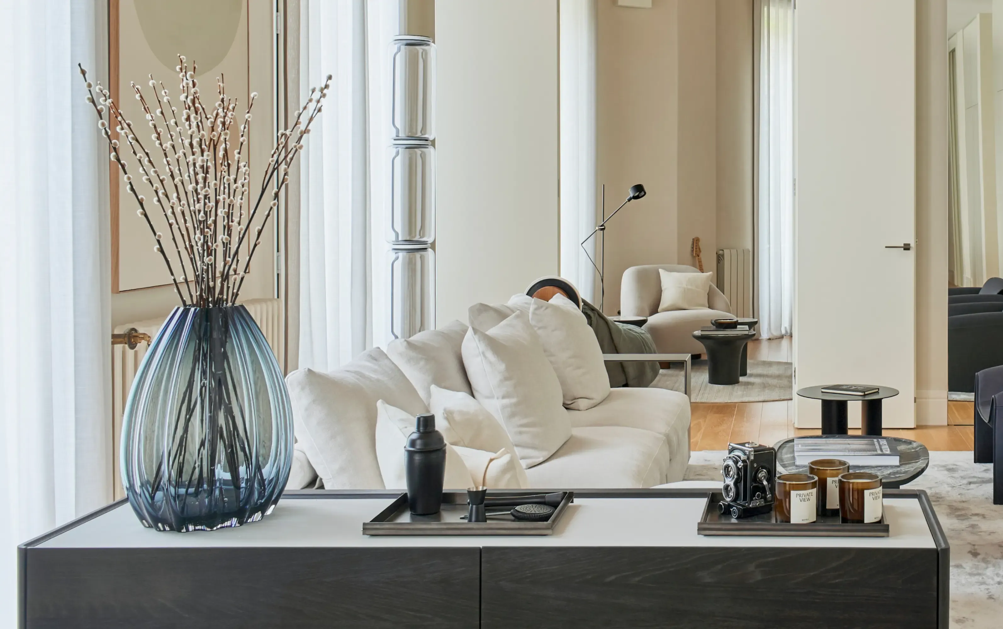 Bright living room with panoramic views, contemporary armchairs and floral arrangement