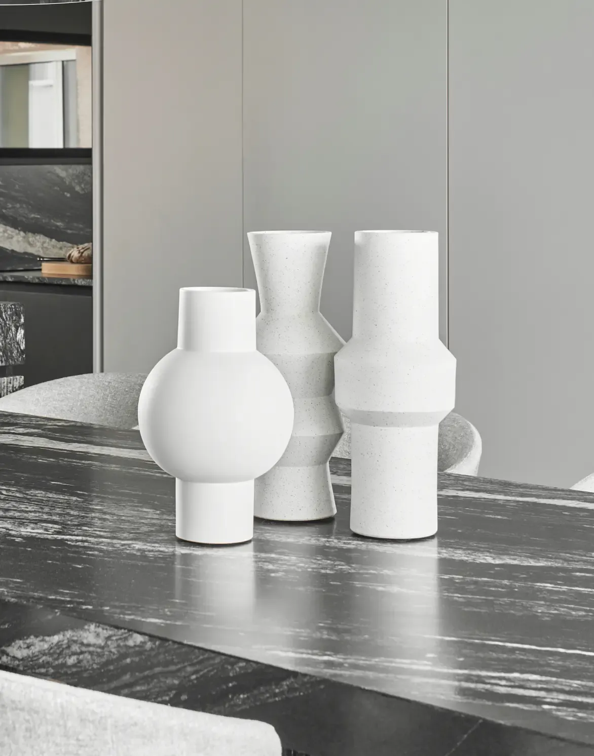 Contemporary ceramic vases with sculptural shapes on dark marble dining table
