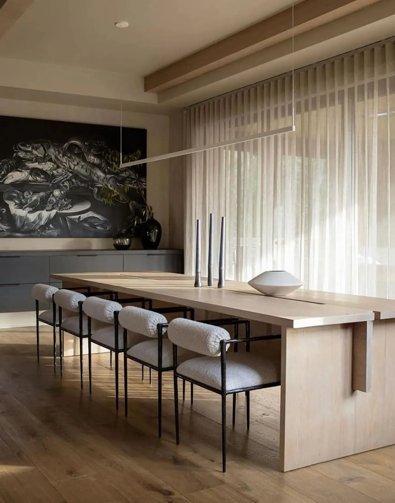 Contemporary dining room with light wood table, metal-framed chairs, and modern artwork.
