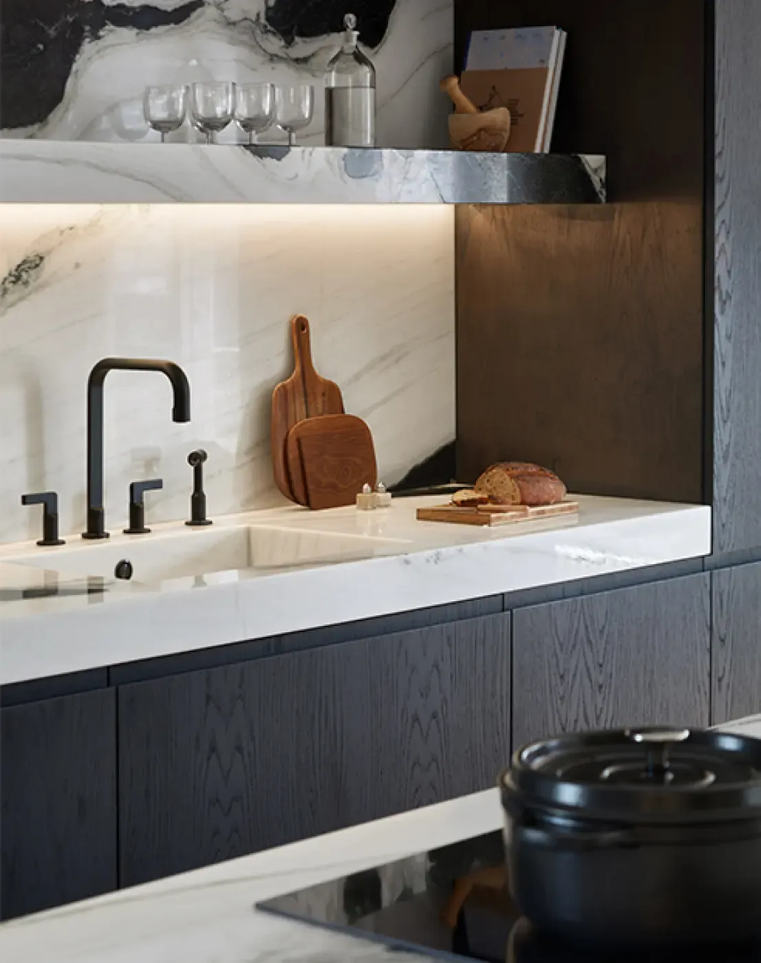 Close-up of marble kitchen counter with integrated sink, black fixtures, and wooden cutting board adding warmth to sleek modern design.
