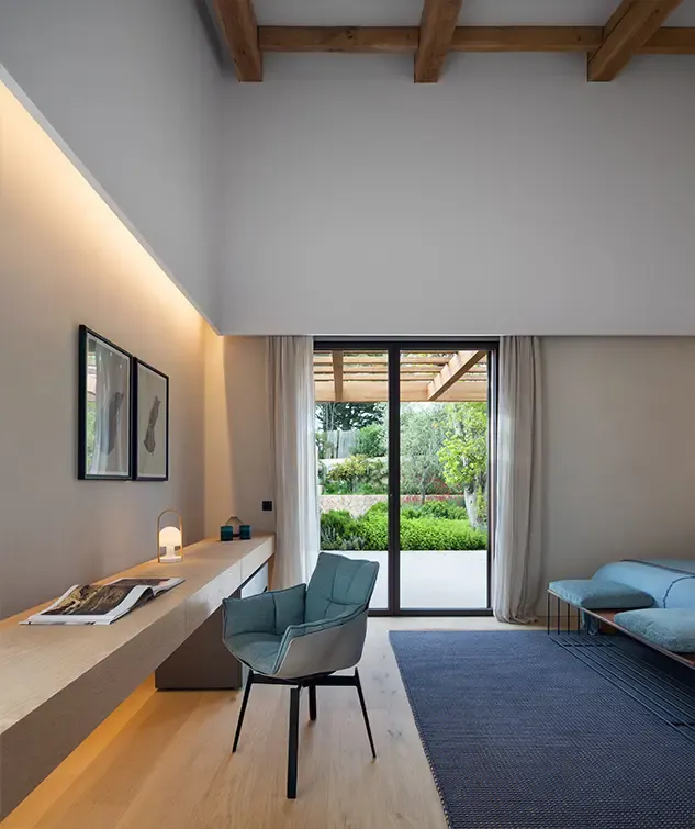Contemporary study with built-in wooden desk, modern chair, large window opening to garden with pergola.