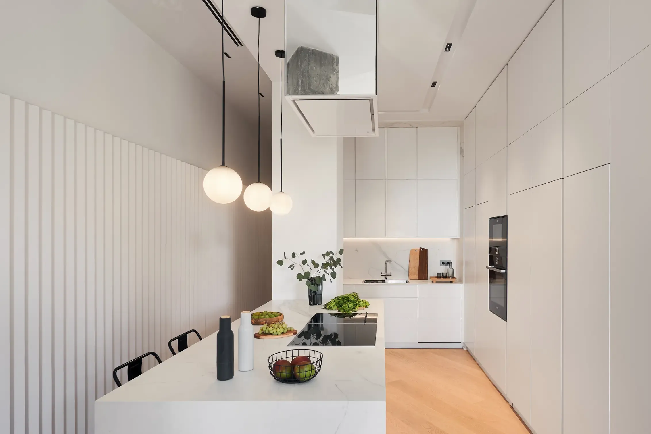 Minimalist kitchen with white cabinetry, marble island, pendant lighting, and modern appliances creating a sleek contemporary interior design.