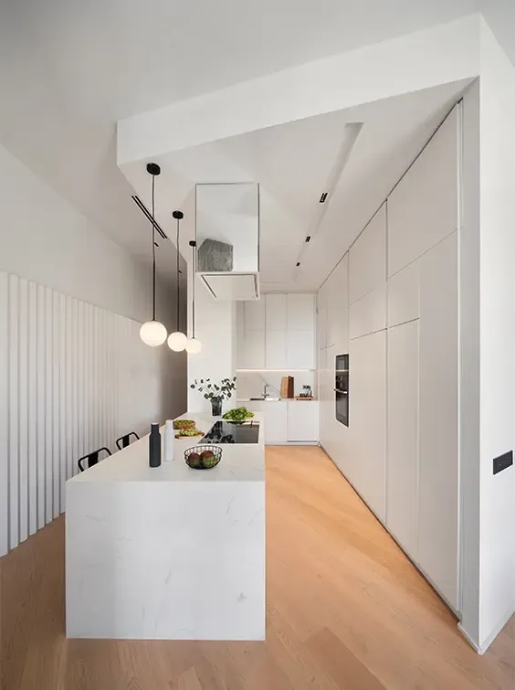 Minimalist kitchen with marble island, pendant lighting, integrated cabinetry, and wooden flooring highlighting sleek luxury apartment design.