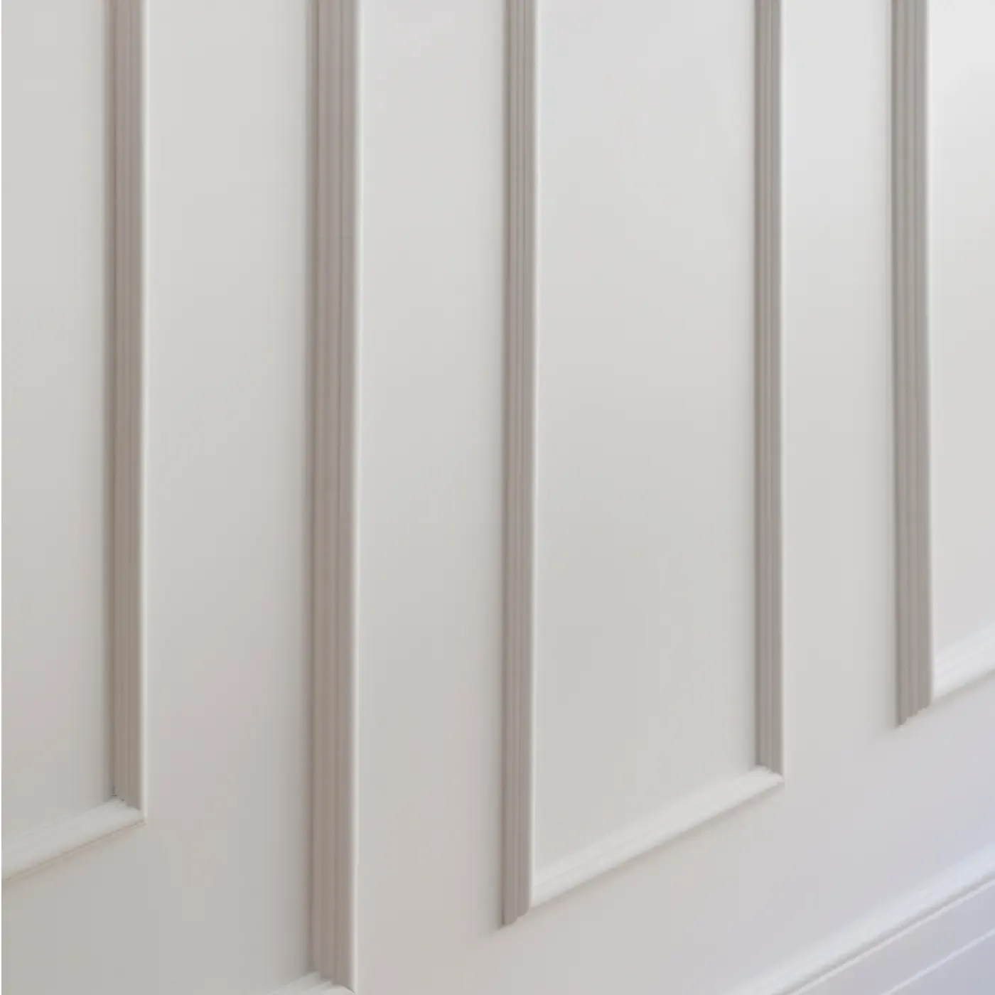 Close-up of white paneled wall with elegant molding details, reflecting timeless architectural craftsmanship.