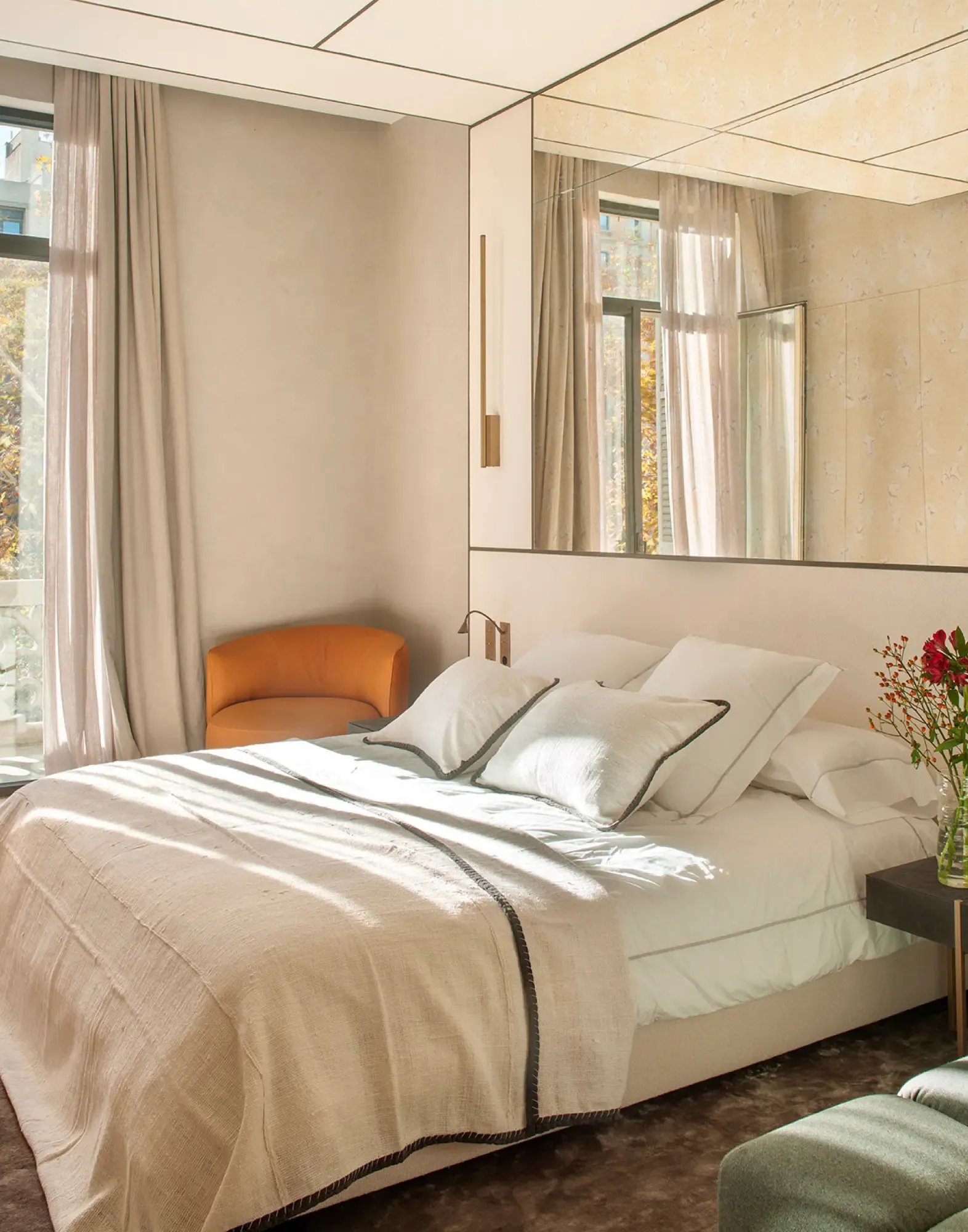 Bright bedroom with soft linens, modern lighting and accent chair in warm Mediterranean tones