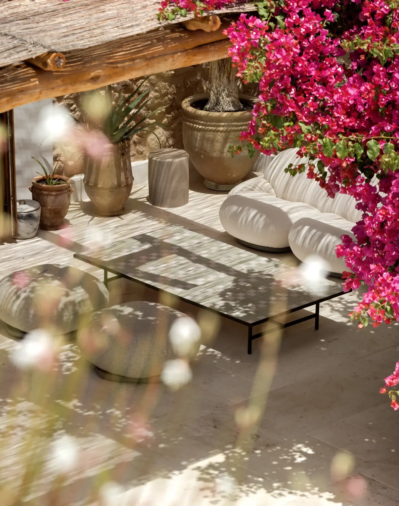 Mediterranean outdoor lounge with natural textures, bougainvillea flowers and relaxed furniture set in Ibiza