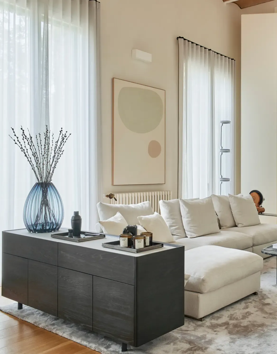 Bright living room with white sofa, abstract artwork and modern sideboard in luxury residence