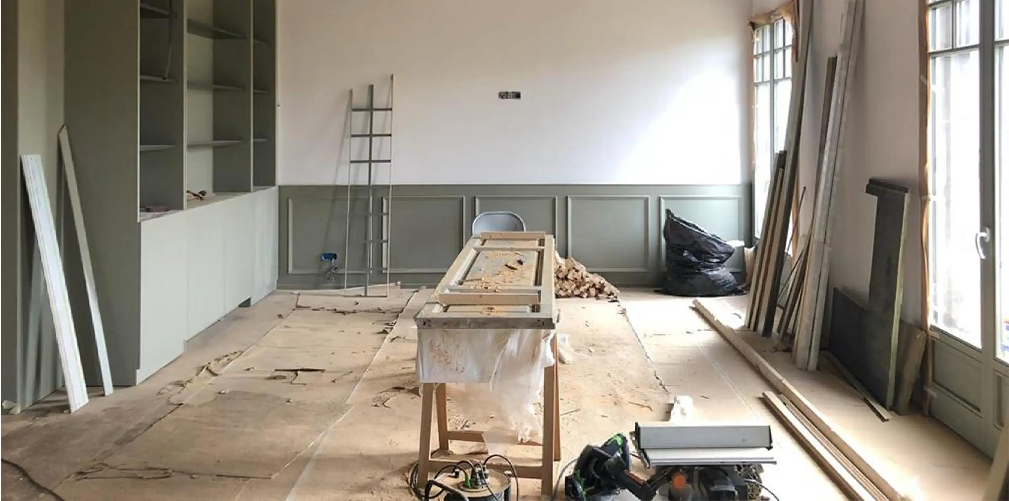 Office under construction with custom cabinetry, exposed beams, and classic window frames in Barcelona’s Eixample district.