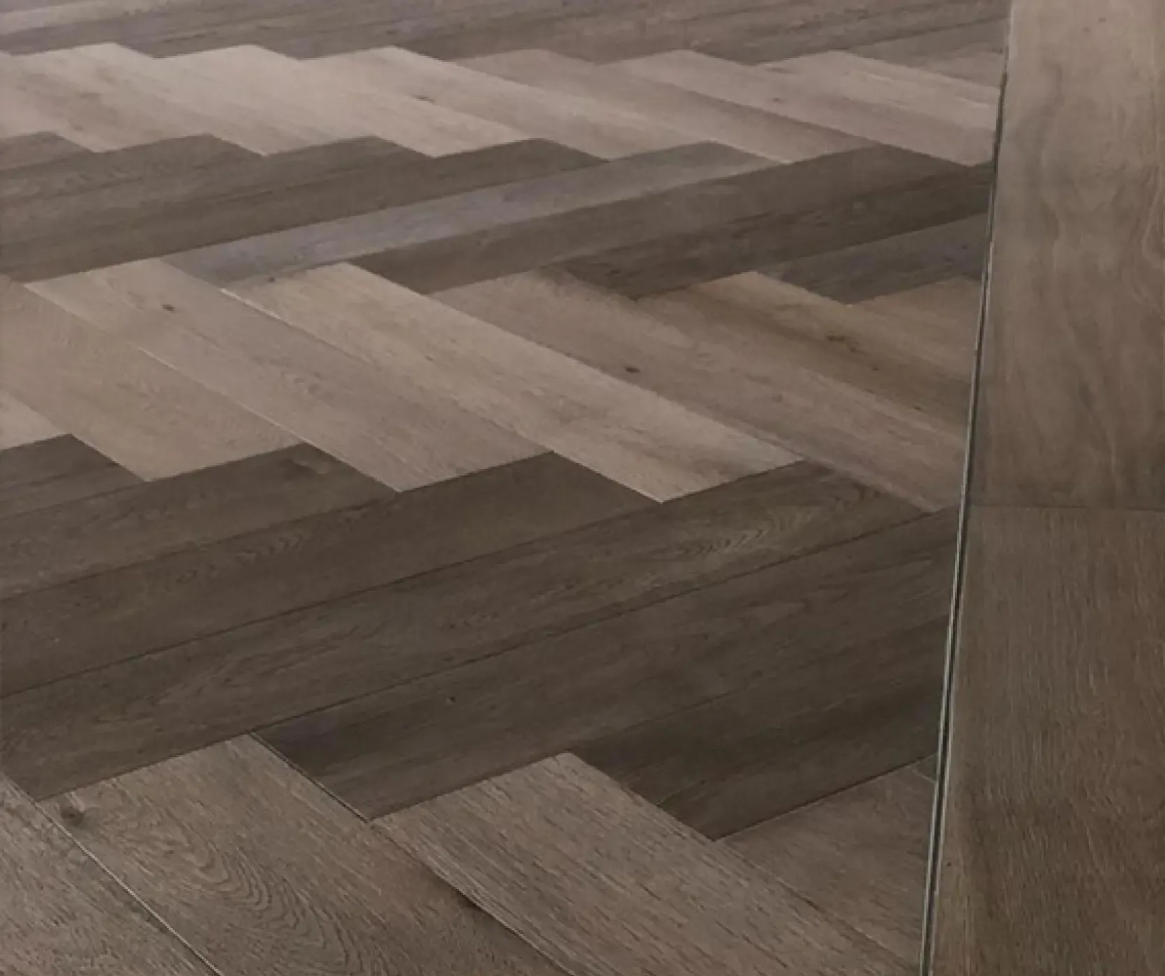 Detail of herringbone oak flooring with perimeter frame, highlighting craftsmanship and material quality in the office renovation.
