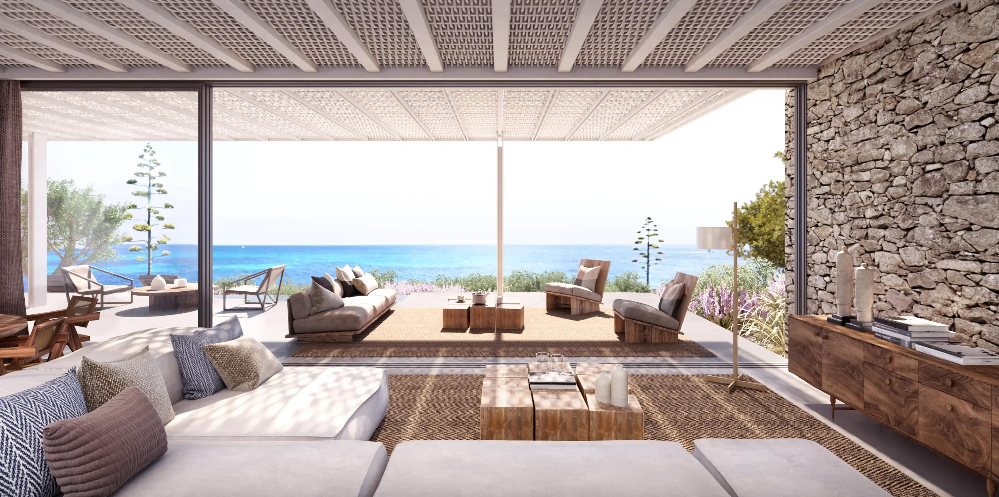Seaside lounge with minimalist furniture, stone walls, and panoramic views of the Mediterranean horizon.